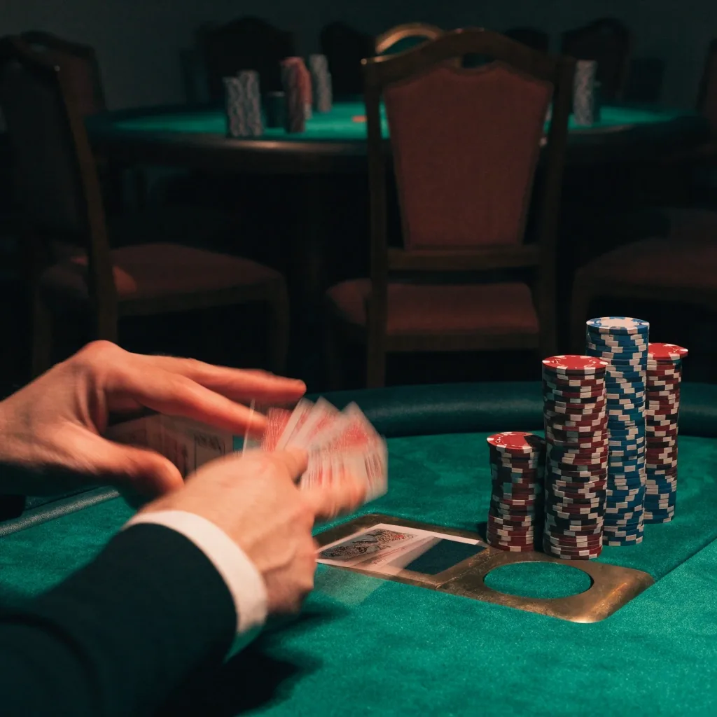 Stohované žetony a odkrytá karta na zeleném sukně pokerového stolu